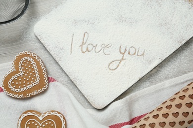 Board with phrase I Love You written in flour, flat lay composition on table
