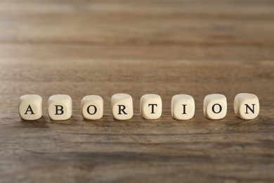 Word Abortion made of cubes on wooden table, closeup