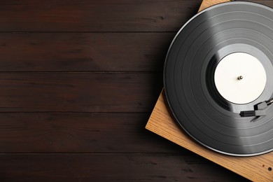 Turntable with vintage vinyl record on wooden background, top view. Space for text