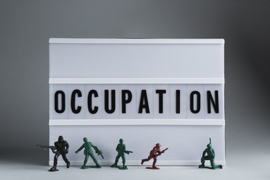 Photo of Lightbox with word Occupation and toy soldiers on light grey background