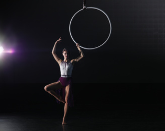 Young woman performing acrobatic element on aerial ring indoors. Space for text