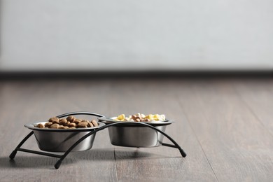 Photo of Bowls with dry dog food on wooden floor indoors, space for text