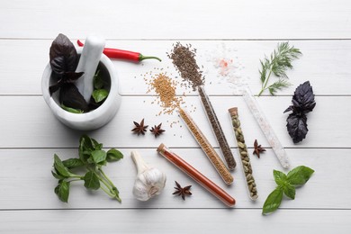 Flat lay composition with various spices, test tubes and fresh herbs on white wooden background