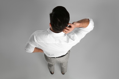 Businessman in formal clothes on grey background, back view