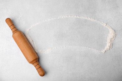 Rolling pin and flour on light grey table, top view. Space for text