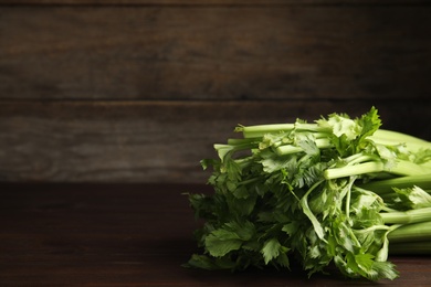 Photo of Fresh ripe green celery on wooden table. Space for text