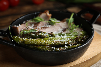 Tasty meat served with asparagus and sprouts in portioned frying pan on table, closeup