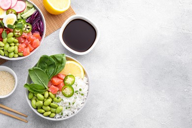 Poke bowl with salmon, edamame beans and rice on light grey table, flat lay. Space for text