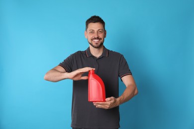 Man holding red container of motor oil on light blue background