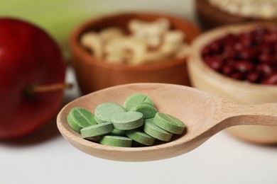 Wooden spoon of pills over foodstuff, closeup. Prebiotic supplements