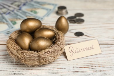 Golden eggs, money and card with word Retirement on white wooden table. Pension concept