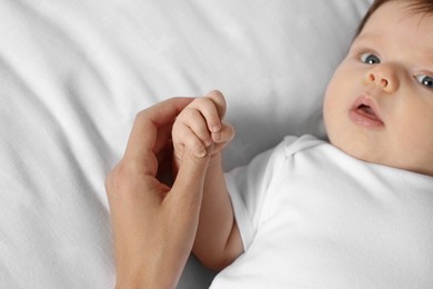 Photo of Mother holding hand of her little baby on bed, closeup