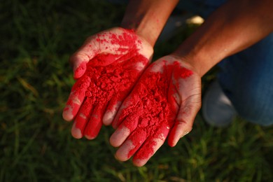 Photo of African American man with red powder dye outdoors, closeup. Holi festival celebration