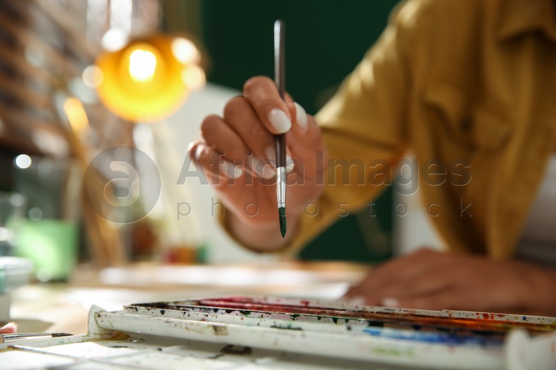 Young woman drawing with watercolors at table, closeup