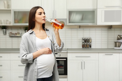 Future mother drinking alcohol in kitchen. Bad habits during pregnancy