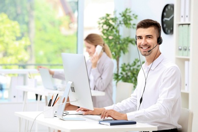 Male receptionist with headset at desk in office