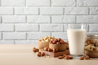 Vegan milk and different nuts on wooden table. Space for text