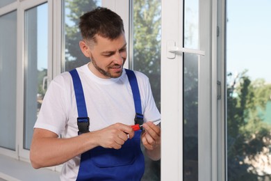 Worker adjusting installed window with screwdriver indoors