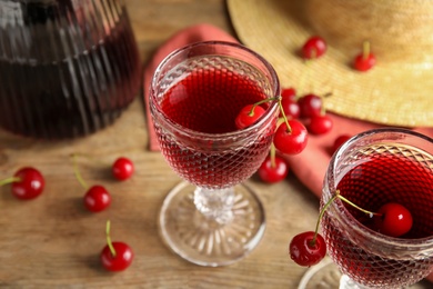 Photo of Delicious cherry wine with ripe juicy berries on wooden table