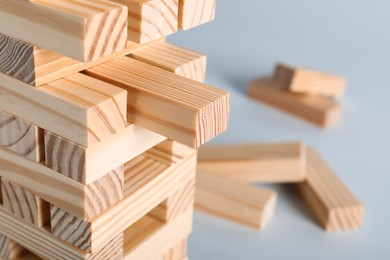 Jenga tower made of wooden blocks on grey background, closeup. Space for text