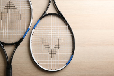 Tennis rackets on wooden table, flat lay. Sports equipment