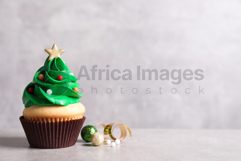 Photo of Christmas tree shaped cupcake and decor on light grey background. Space for text