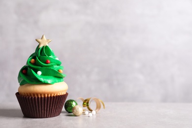 Christmas tree shaped cupcake and decor on light grey background. Space for text