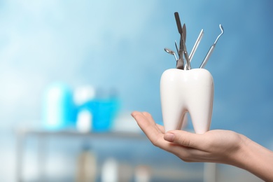 Dentist with tooth shaped holder full of professional tools in clinic, closeup. Space for text