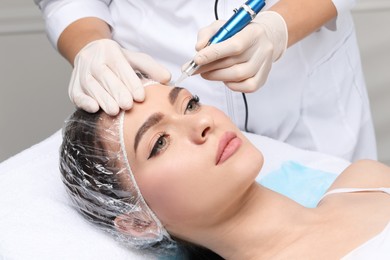 Young woman during procedure of permanent eyebrow makeup in beauty salon, closeup
