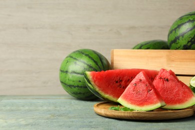 Delicious ripe whole and cut watermelons on wooden table, space for text