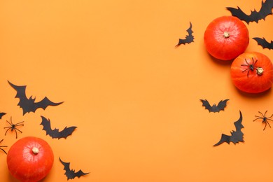 Flat lay composition with pumpkins, paper bats and spiders on orange background, space for text. Halloween decor