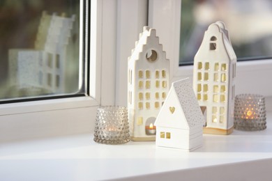 Photo of Beautiful house shaped candle holders on windowsill indoors, space for text