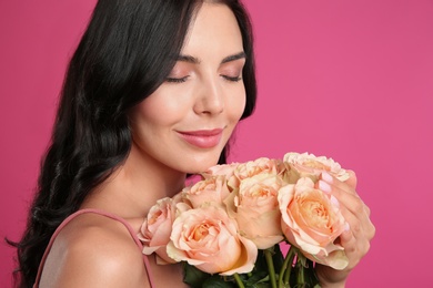 Young woman with beautiful bouquet on pink background