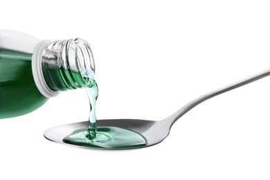 Pouring syrup into spoon from bottle isolated on white, closeup. Cough and cold medicine