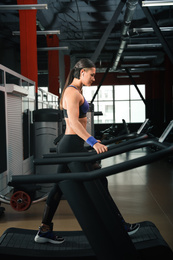 Young woman working out on treadmill in modern gym