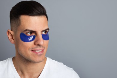 Man with blue under eye patches on grey background. Space for text