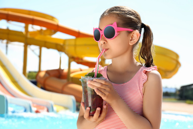 Girl with delicious refreshing drink in water park
