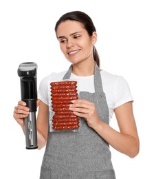 Beautiful young woman holding sous vide cooker and sausages in vacuum pack on white background