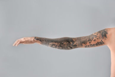 Man's arm with stylish tattoos on grey background