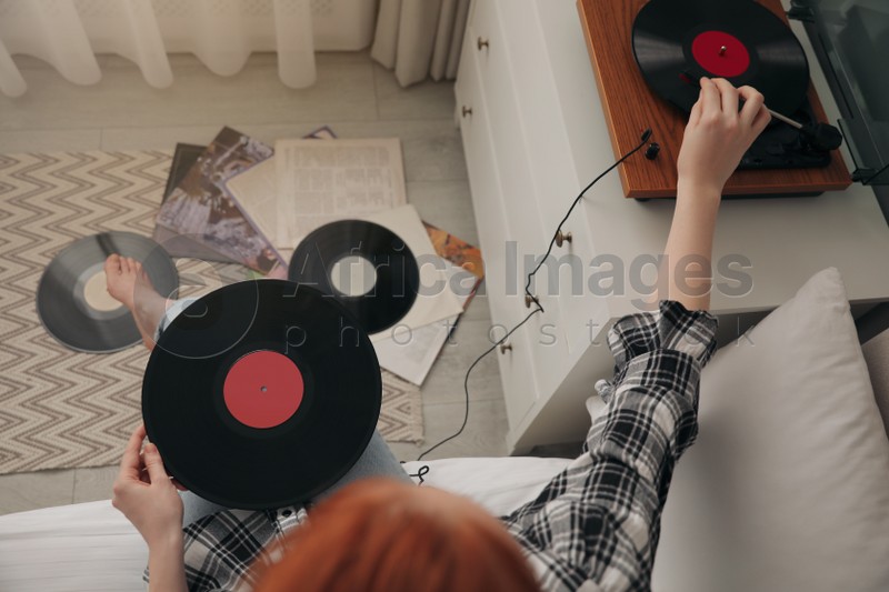 Young woman listening to music with turntable in bedroom, above view