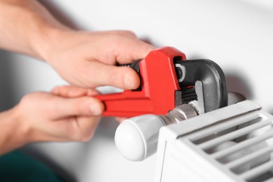 Professional plumber using adjustable wrench for installing new heating radiator, closeup