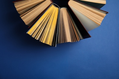Hardcover books on blue background, flat lay