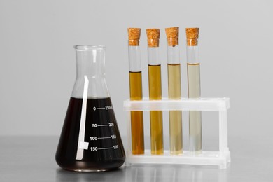 Photo of Different laboratory glassware with brown liquids on light grey background