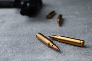 Bullets and handgun on light grey table, closeup. Space for text