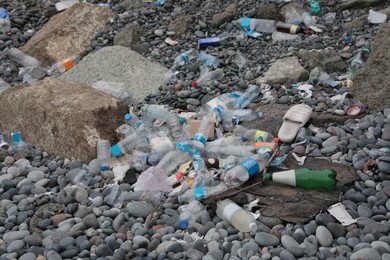 Photo of Garbage scattered on pebbles outdoors. Recycling problem