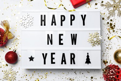 Lightbox with phrase Happy New Year and festive decor on white background, flat lay