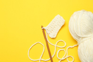 Knitting and crochet hook on yellow background, flat lay. Space for text