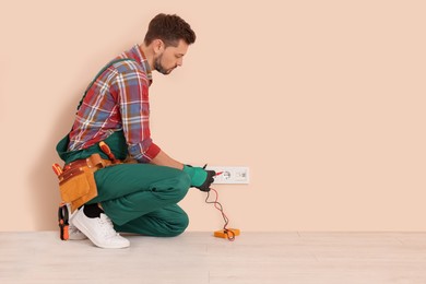 Electrician in uniform with tester checking voltage indoors. Space for text