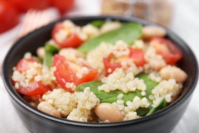 Photo of Delicious quinoa salad with tomatoes, beans and spinach leaves, closeup