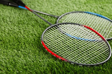 Badminton rackets on green grass outdoors, closeup